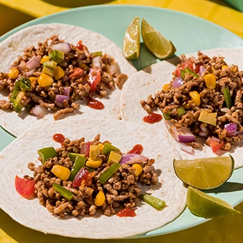 An image of making taco meat and being prepared on a plate with slices of lime