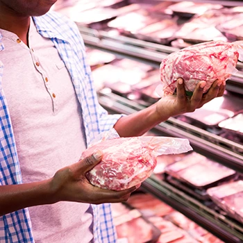 An image of a man comparing meat prices at a store