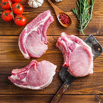 A top view image of three pork chops with other ingredients