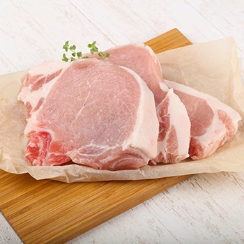 An image of pork chops on top of a wooden board