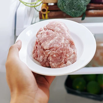 An image of a person refreezing raw ground meat inside a fridge