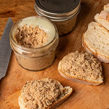 Jars of rillettes and slices of bread on a wooden table