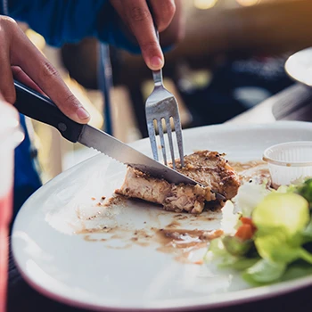 An image of a person slicing meat on a plate