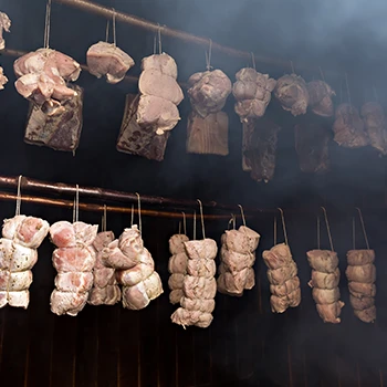 An image of hanging meats being smoked