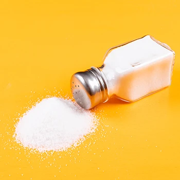 An image of salt and salt shaker on a yellow background