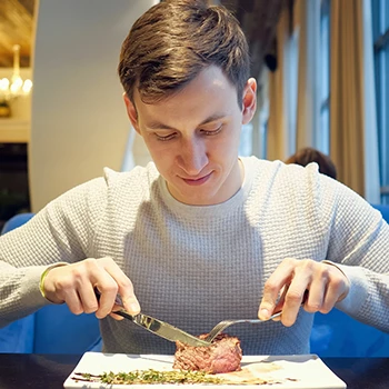 An image of a guy eating a delicious steak