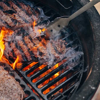 An image of a person cooking meat using a kamado grill