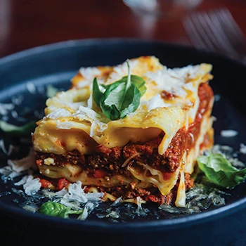 Beef cheek lasagne dish on a black plate