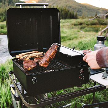 An image of a person cooking using a portable grill outdoors