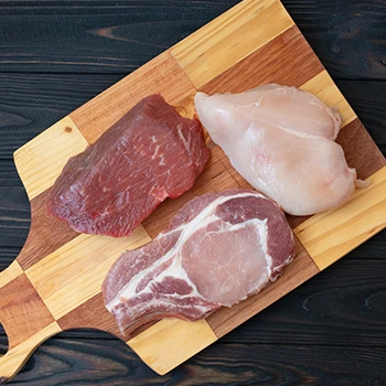 A top view image of chicken, beef, and pork meat on a wooden board