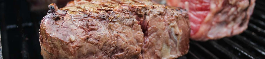 A close up photo of filet mignon being cooked on a grill
