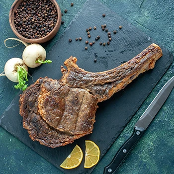 A top view image of cooked prime rib meat with lime slices and knife beside