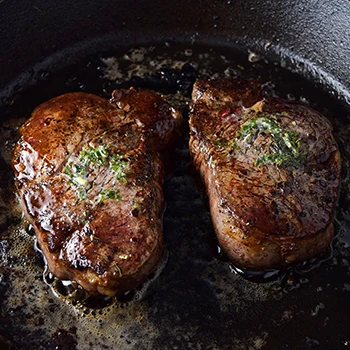 Butter-basted filet mignon on an iron skillet pan