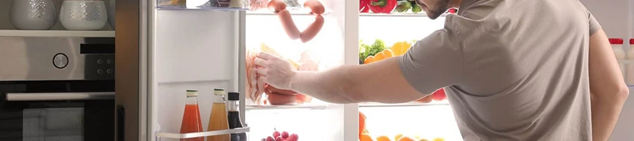 A man stores a cooked ham in the fridge
