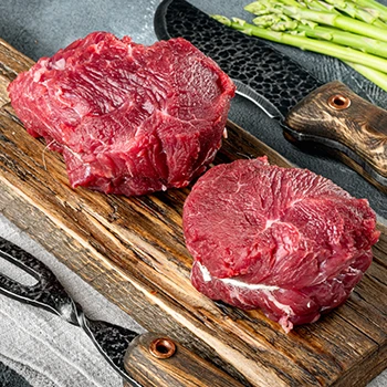 Raw filet mignon meats on top of a wooden board