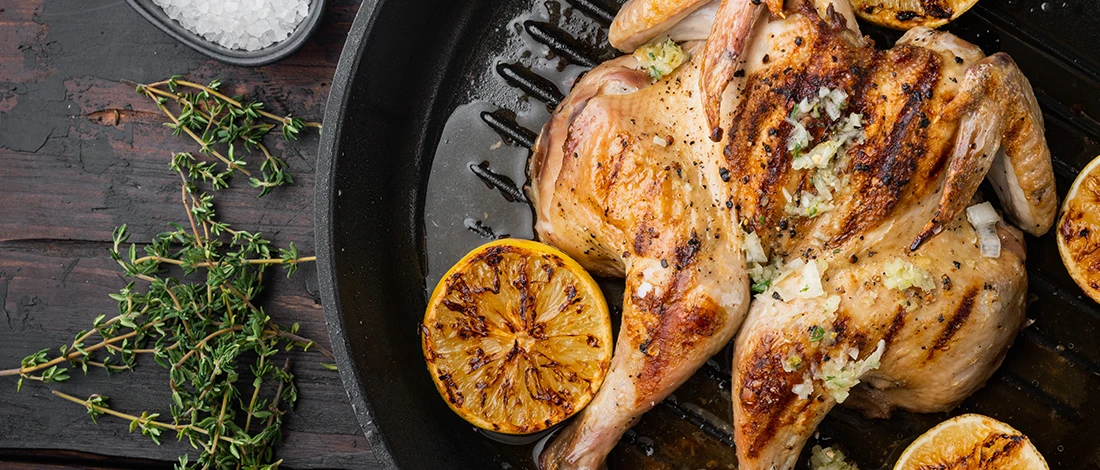 A delicious chicken rotisserie with lemons on a pan