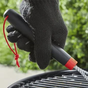 A close up shot of a man holding a grill brush from the handle