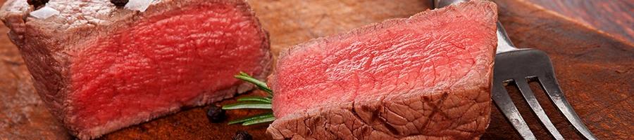 A difference between steak and beef sliced into two on top of a wooden board