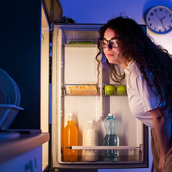 A woman checking the fridge at night time