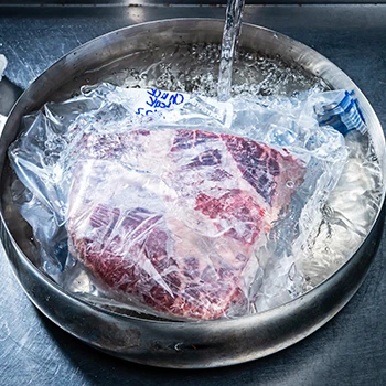Thawing frozen meat by placing it on a running water