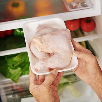 A woman storing chicken meat on the freezer