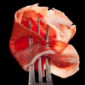 A close up shot of a prosciutto ham on a fork