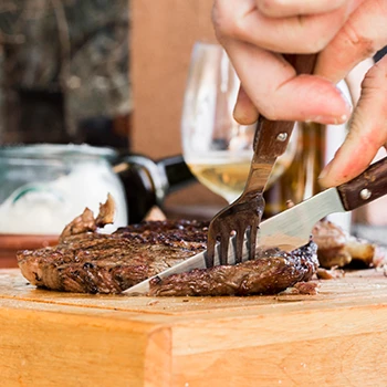 A person slicing a perfectly cooked steak on a cutting board