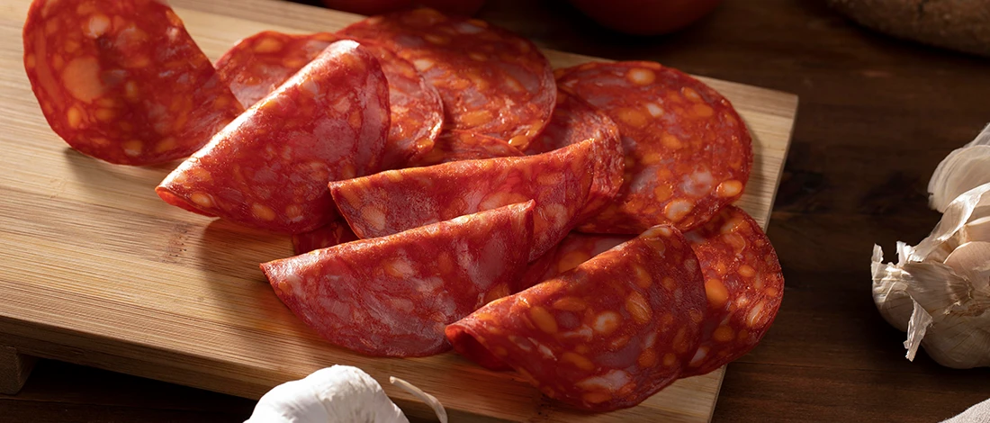 Thinly sliced chorizo on a wooden board