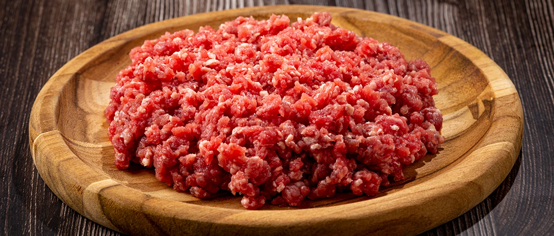 Raw ground beef on a wooden plate