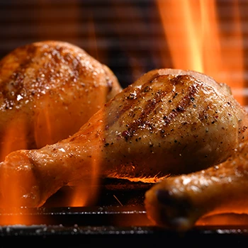 Chicken being cooked on a high-flamed grill