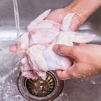 A close up shot of a chicken meat being rinsed in running water