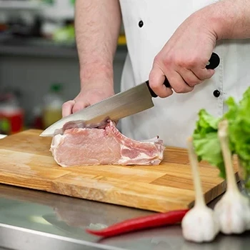A chef slicing meat using a cutting board and a knife