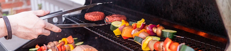 A woman putting different foods on the grill