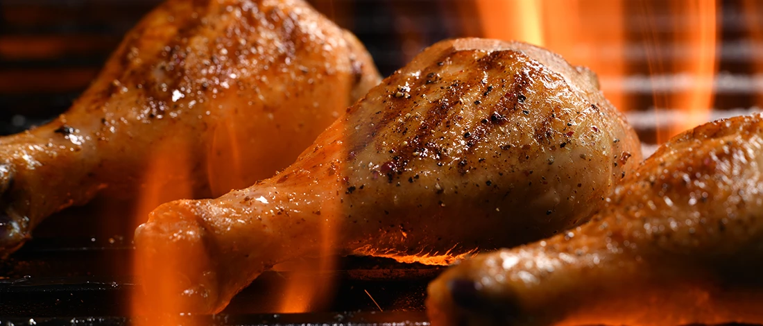 A close up shot of chicken drumsticks being cooked on a grill