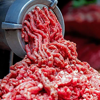 A close up shot of minced meat coming out of a meat grinder