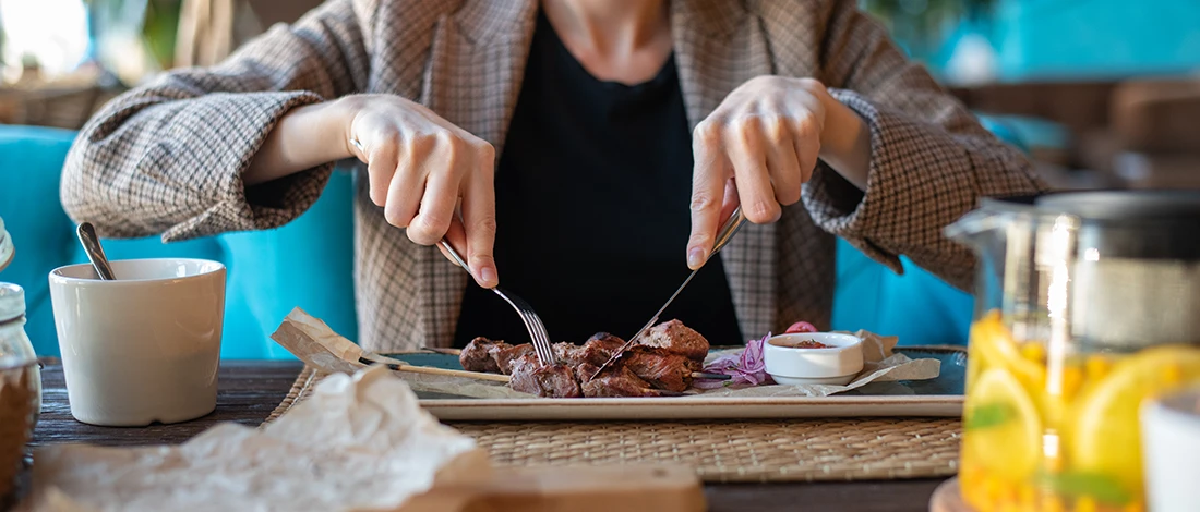 A woman eating meat on a table