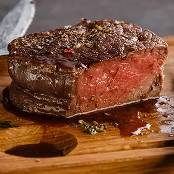 A close-up shot of a steak releasing red juice on a wooden board