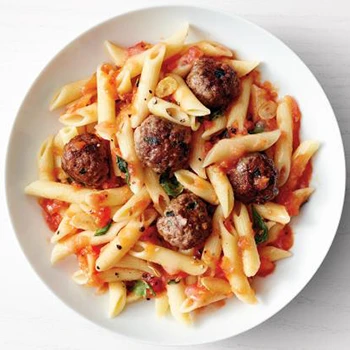 A top view of pasta with vodka sauce topped with meatballs