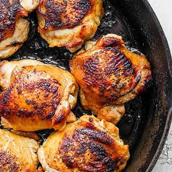 Chicken meat being cooked on an cast iron skillet