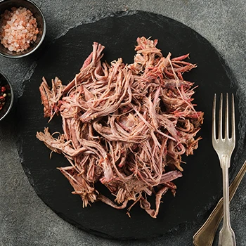 A top view of pulled pork on a black plate