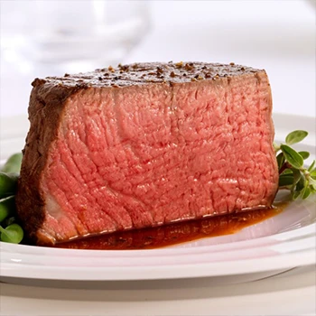 A perfectly cooked medium rare steak on a white plate releasing red juice at the bottom