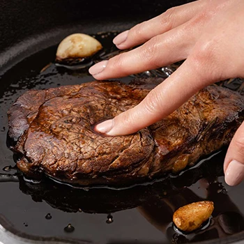 A woman is doing a texture test to tell if pork is cooked