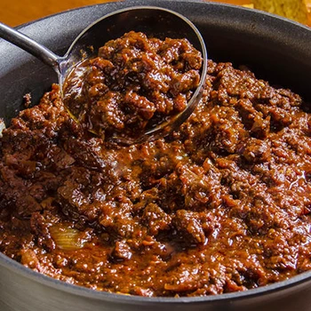 A person cooking chili con carne using minced meat