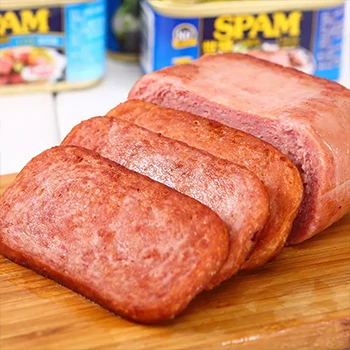 Slices of spam meat on a wooden board and its can in the background