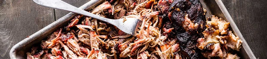 A top view of pulled pork in a metal sheet pan