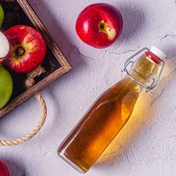 A top view of apple cider vinegar and some apples used for spritz brisket