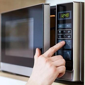 A person sets the microwave settings before defrosting the meat