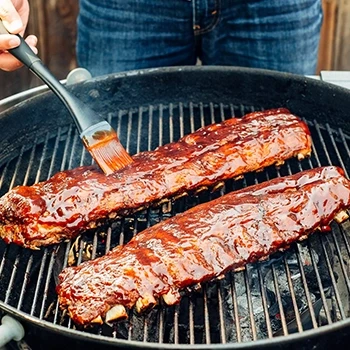 A person cooking baby back ribs