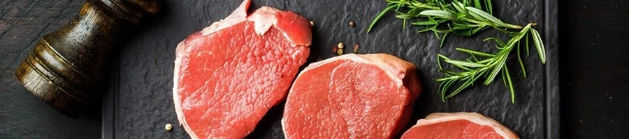 A top view of eye of round steak on a black slate