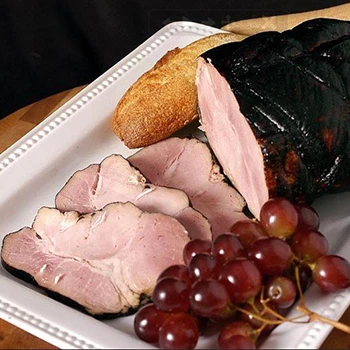 Black forest ham on a white plate with bread and grapes